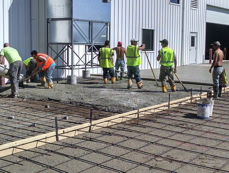 Concrete Crew Pouring a Large Concrete Slab Outside a Commercial Building